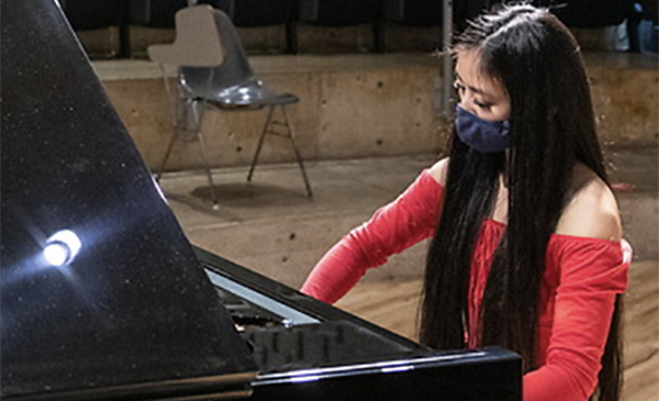 masked performing arts student playing piano